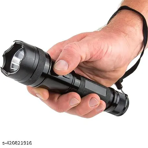 Hand holding a black Defense Flashlight with textured grip, reinforced bezel and wrist strap
